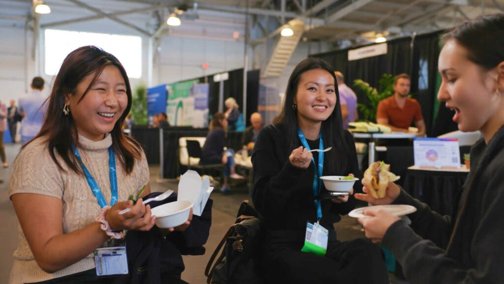Year in review 2023 17 Three people stand in a group at the good food conference, laughing and talking as they eat food from paper plates.