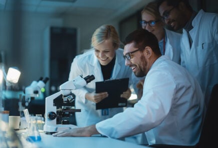 Scientists looking at a microscope in a lab